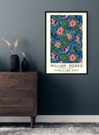 Framed William Morris flower exhibition poster with intricate floral design on a dark wall above a wooden dresser.