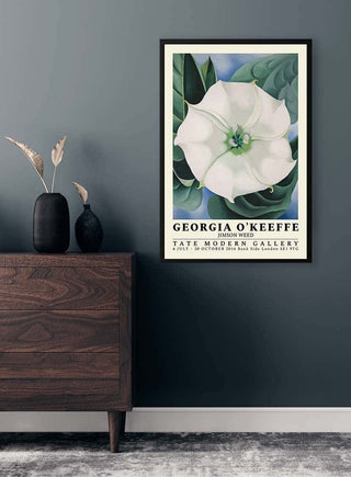 Framed Jimson Weed - Georgia O'Keeffe art print displayed on a dark wall above a wooden dresser.