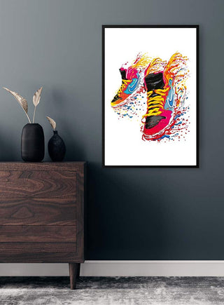 Colorful flaming sneakers artwork in black frame displayed on a modern dark wall above a wooden dresser.