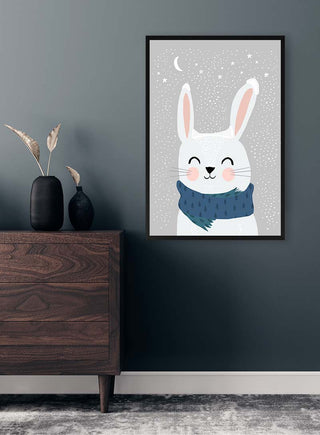 Framed Snow Bunny - Treechild print featuring a smiling white bunny in a blue scarf, displayed above a dresser.