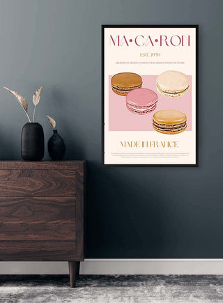 Framed macaron print featuring colorful macarons and stylish text, displayed above a modern wooden dresser.
