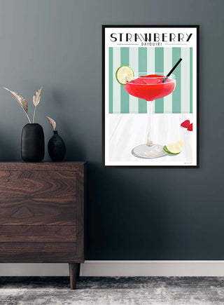 A framed Strawberry Daiquiri ByKammille print with a red cocktail and lime, displayed on a modern wall.