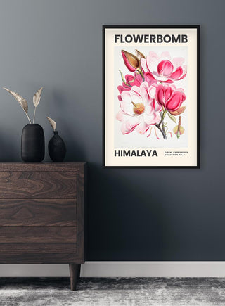 Framed Flowerbomb Himalaya art poster with pink and white flowers on a dark wall above a wooden dresser.