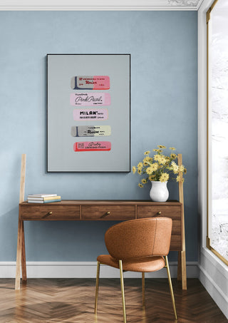 Erasers Art Print displayed in a modern room above a wooden desk with flowers and a brown chair.