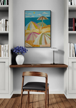 Vamos ala Beach by Eleanor Baker framed on a wall above a desk with bookshelves, flowers, and lamp.
