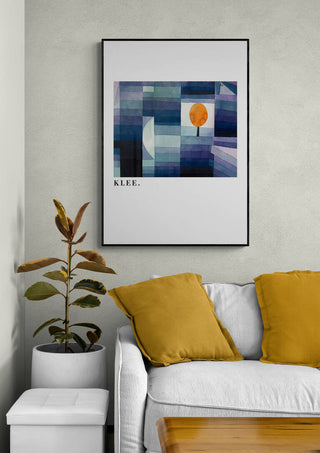 Framed print of Paul Klee’s “The Harbinger of Autumn” displayed above a modern sofa with yellow pillows.