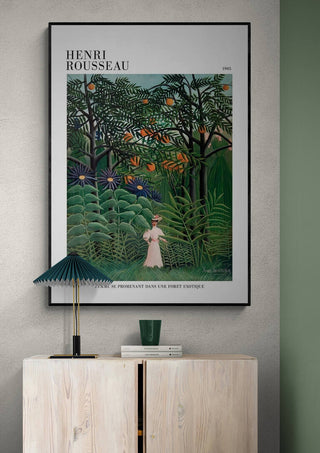 Framed print of "Femme Se Promenant" by Henri Rousseau displayed above a wooden cabinet and table lamp.