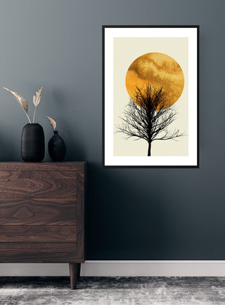 Poster of a lone tree silhouette against an orange sunrise, framed on a dark wall above a wooden dresser.