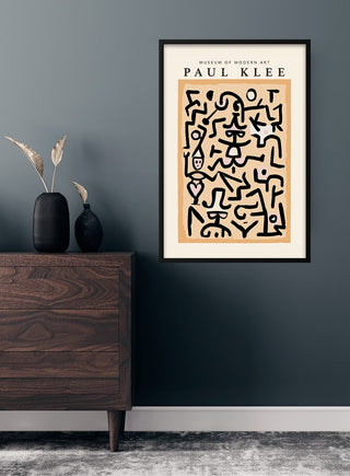 Paul Klee art poster with abstract black line figures, framed and hung above a wooden dresser in a modern living room.