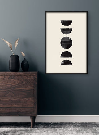 Black Circles Plakat artwork with four black semicircles, framed and hung on a dark wall above a wooden dresser.