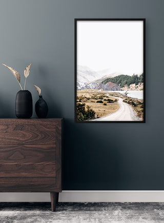 Framed Mountain road Plakat featuring a scenic winding road through mountains, displayed above a wooden dresser.