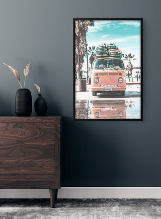 Framed poster of a vintage van with surfboards on a beach, displayed above a wooden dresser in a modern room.