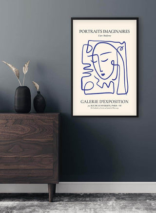 Framed Portraits Imaginaires Blue Plakat with abstract face line art hanging above a wooden dresser.