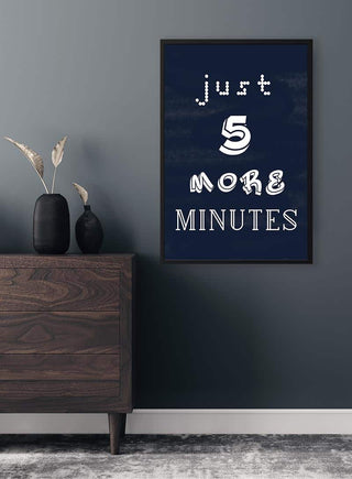 Framed "Just 5 More Minutes" gamer poster hanging on a dark wall above a wooden dresser with vases.