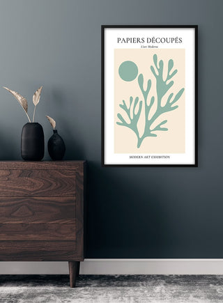 Minimalist poster of green coral and sun, inspired by Matisse, hanging above a wooden dresser on a dark wall.