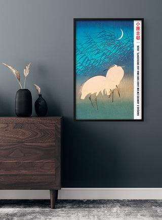 Framed Ohara Koson "Two Cranes" plakat on wall above wooden dresser in modern room.