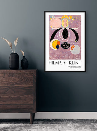 Framed Hilma af Klint - Adulthood No. 6 poster with abstract shapes on a pink background, hung on a dark wall.