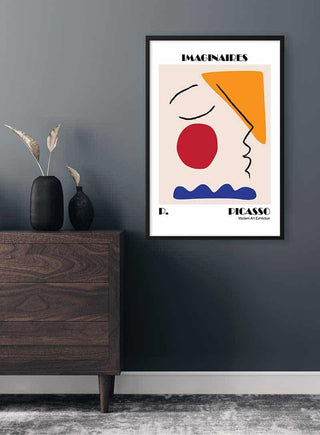 Framed Picasso inspired "Imaginaires" exhibition poster with abstract face art on a modern interior wall.
