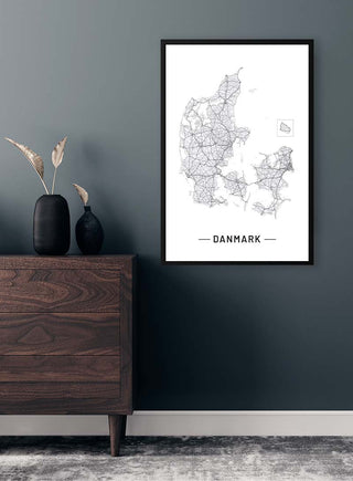 Framed Danmarkskort plakat on a dark wall above a wooden dresser with minimalistic decor.