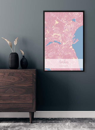 Framed Arhus By Plakat Lyserød map poster with pink tones displayed on a dark wall above a wooden dresser.