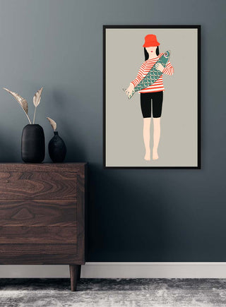 Minimalist artwork of a person in red hat holding a fish, displayed on a wall above a wooden cabinet.