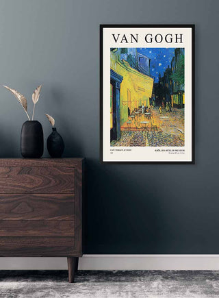 Framed Van Gogh "Café Terrace at Night" poster hanging on a dark wall above a modern wooden dresser.