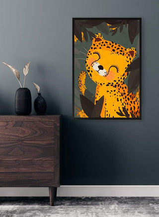 Framed Little Leo leopard art print hanging on a dark wall above a wooden dresser with vases.
