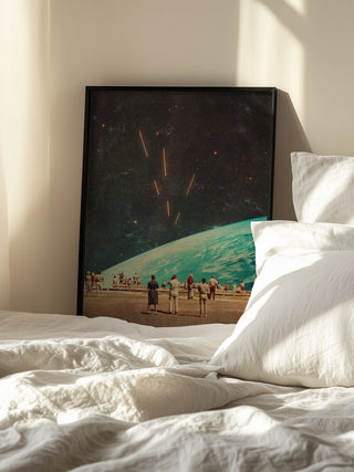 Framed print of "The Others" by Frank Moth leaning on a bedroom wall beside a white bed and pillows.