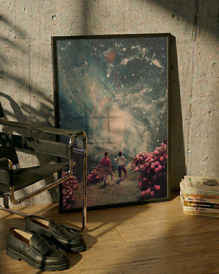 Art print of "There Will Be Light In the End" by Frank Moth, leaning against a wall beside a chair and books.