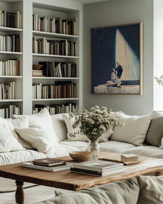 Framed "This Love" by Frank Moth above a cozy sofa in a book-filled living room.