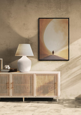 Framed "Deep Thoughts" by David Wolf artwork above a sideboard with lamp in a minimalist room.