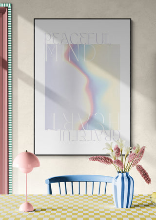 Framed "Peaceful Mind" poster with soft pastel colors, displayed above a table with flowers and a pink lamp.