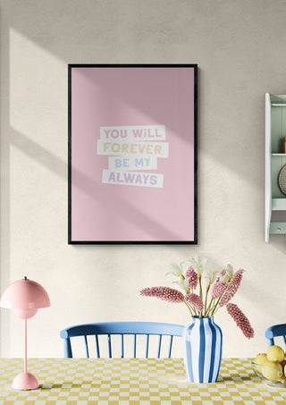 Framed pink wall art with "You will forever be my always" displayed above a pastel dining table setting.