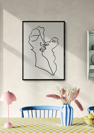 Minimalist wall art of two abstract faces intertwined, displayed above a dining table with flowers and decor.