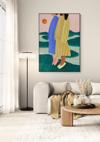 Framed art print of two women in striped dresses by Bea Muller, displayed above a modern living room sofa.