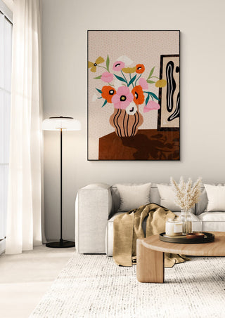 Framed "Flowers On Sideboard" by Bea Muller hanging above a modern sofa in a cozy, light-filled living room.