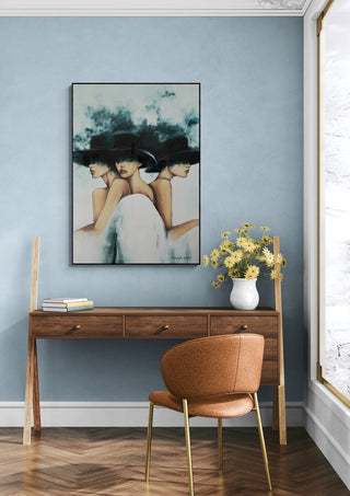 Framed Three Hats by David Wolf artwork on a blue wall above a wooden desk with flowers and books.