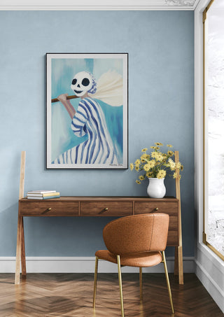Framed Skt. Hans - Martin Zen artwork on blue wall above a wooden desk with flowers and an orange chair.