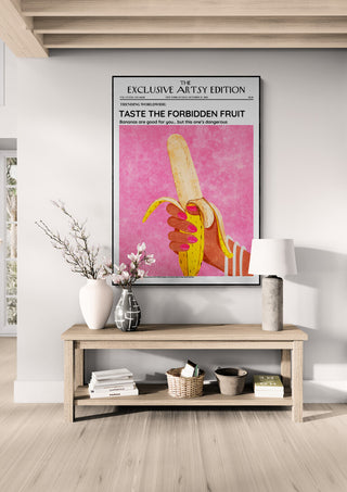 Framed "The Forbidden Fruit Artsy Edition" poster featuring a hand holding a peeled banana, styled on a wall.
