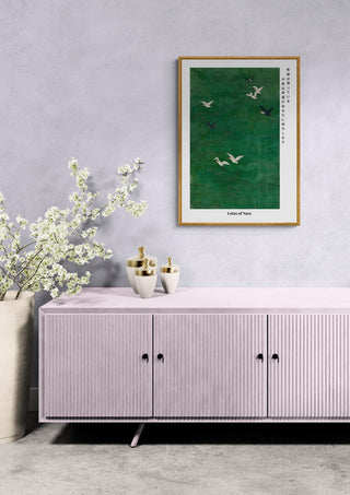 Framed Japandi woodprint "Lotus of Nara" above a pink sideboard with vases and blossoming branches.