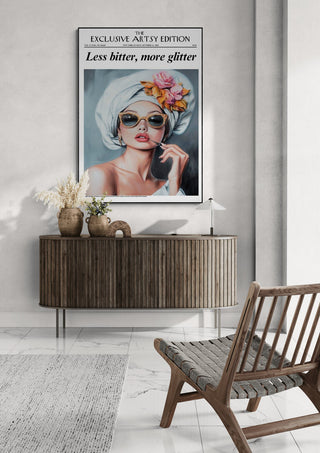 Framed "Less Bitter, More Glitter" Artsy Edition poster displayed above a modern sideboard in a stylish room.