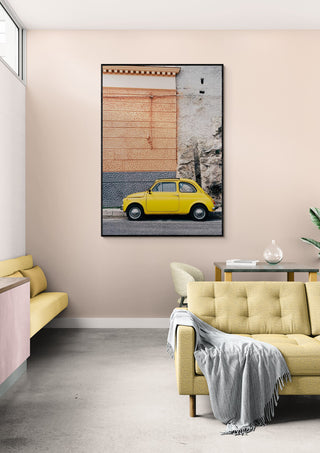Framed print of a yellow car on the Amalfi Coast displayed above a beige sofa in a modern living room.