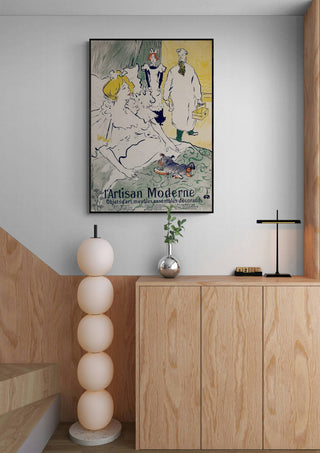 Framed "Artisan Moderne" by Henri de Toulouse-Lautrec hanging above a modern wooden cabinet in a stylish interior.